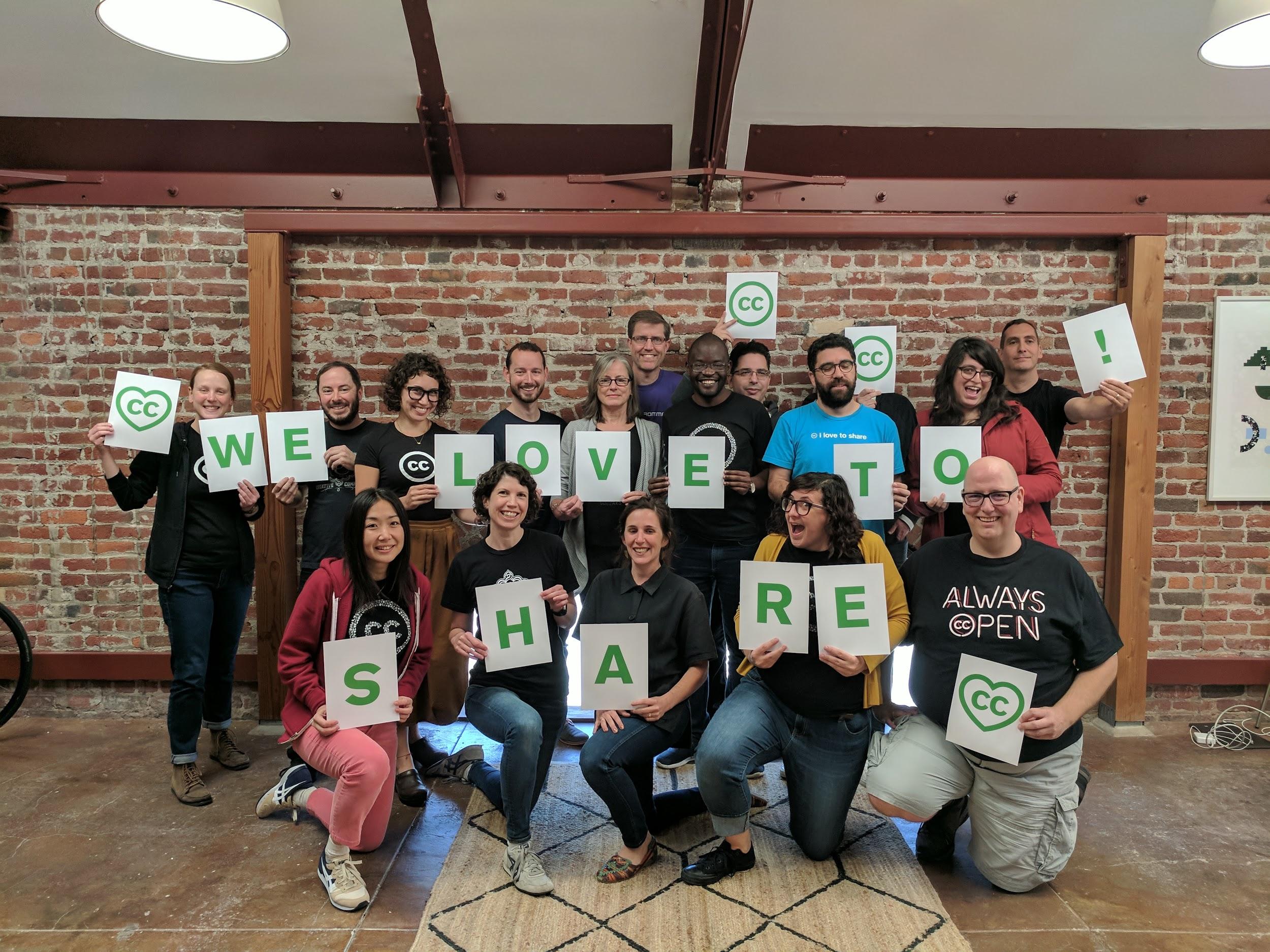 Creative Commons Staff holding signs spelling "We Love To Share"